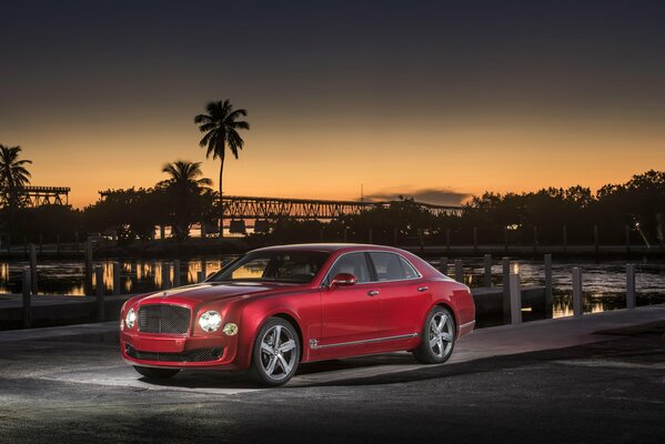 Ein schicker Bentley in roter Farbe auf einem Palmenhintergrund