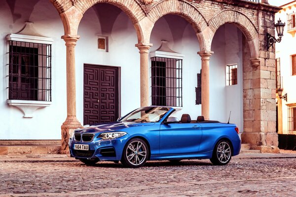 Un convertible azul se encuentra en el fondo de un edificio con columnas