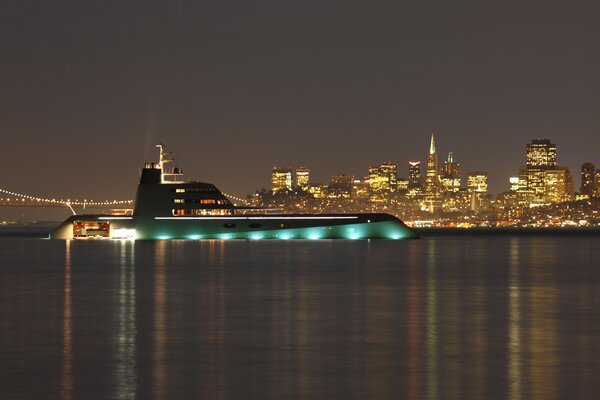 Сепер мега-яхта в вечерних огнях у моста
