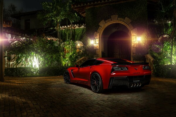 Красная машина chevrolet corvette стоит в тени