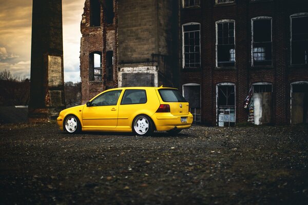 The yellow Volksfagen stopped at an abandoned building