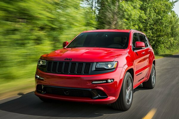 A red wide jeep rushes along the highway