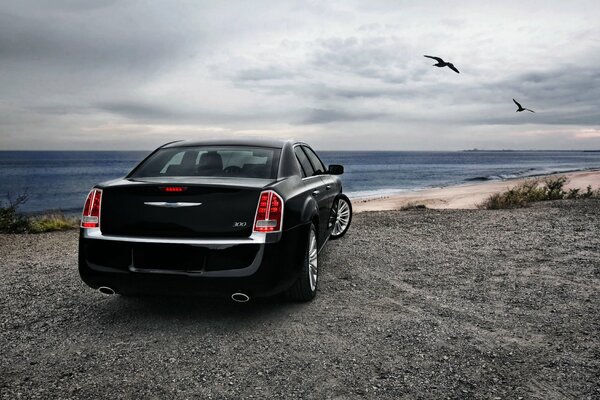 Czarny sedan Chryslera w pobliżu wybrzeża