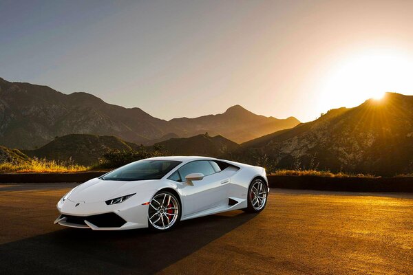 Weißer Lamborghini Huracan im Hintergrund des Sonnenuntergangs inmitten der Berge