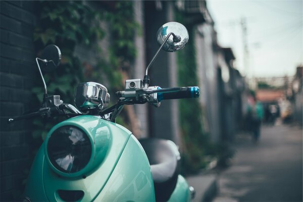 In the foreground is a green scooter, in the background is a street