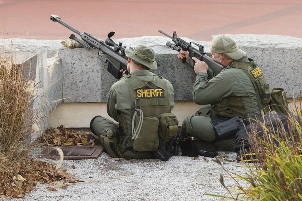 Snipers with weapons behind a concrete floor