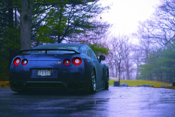 Blue nissan, r35, in the rain on the road rear view