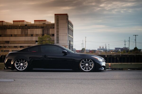 Black infiniti g37 in tuning against the background of the industrial zone