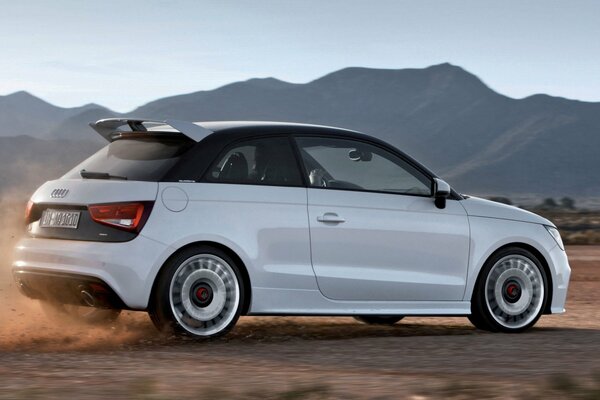 Audi A1 jedzie drogą w górzystym terenie