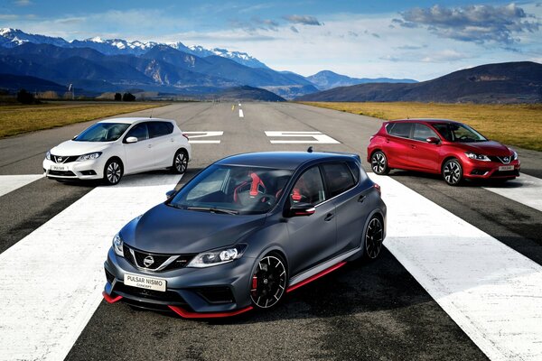 Voitures Nissan de différentes couleurs debout sur la route sur fond de montagnes enneigées