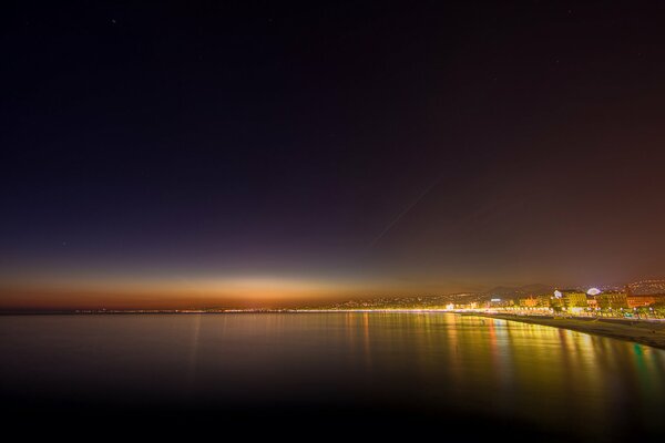 The mirror surface of the ocean under the black night sky