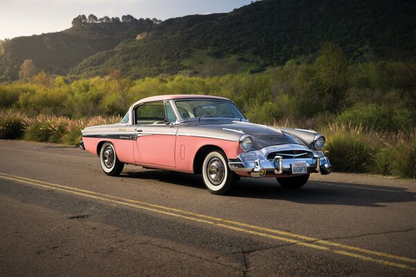Pink retro Studebaker on the background of hills