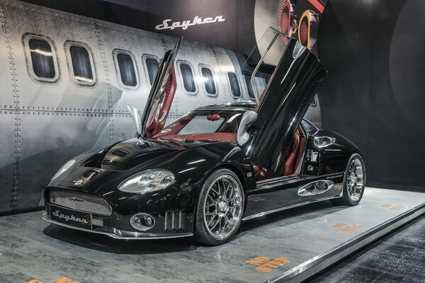 Sports car with open doors on the background of an airplane