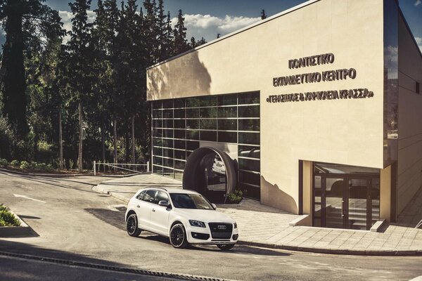 Ein weißer Audi q5 steht neben einem Glasgebäude