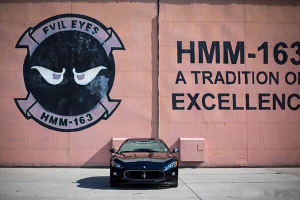 Czarny Maserati z przodu na tle ściany z reklamą