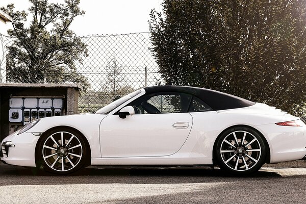 Porsche carrera с 18 дюймовыми дисками и ярко белым цветом в аркий сонечный ден