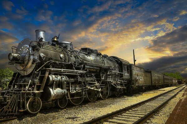 Das Bild der Lokomotive auf dem Hintergrund der Eisenbahn und des Sonnenuntergangs