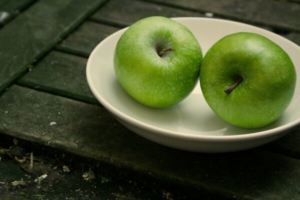 Zwei grüne saftige Äpfel auf einem Teller