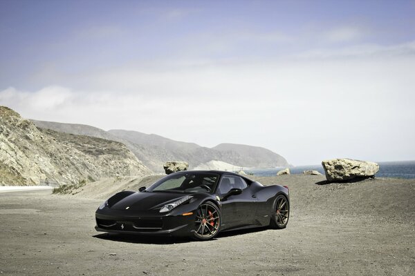 Ferrari noir sur fond de montagnes et ciel bleu