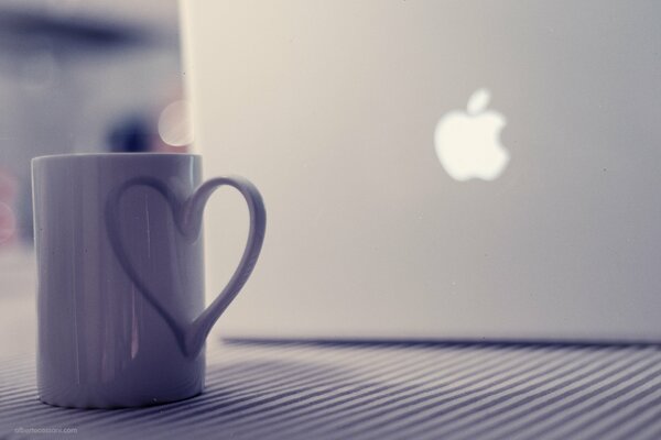 Una taza cerca de la computadora portátil se encuentra en la mesa