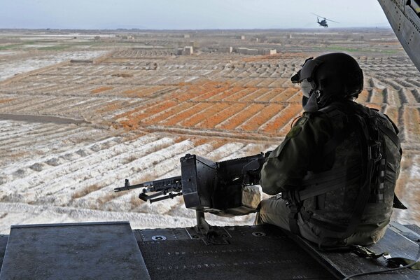 A soldier with a machine gun looking at the horizon