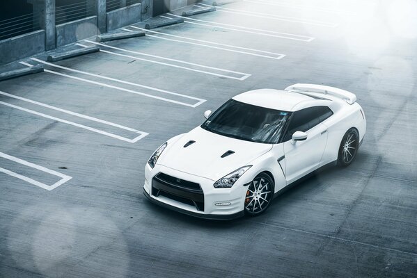 White Nissan in the parking lot, front and top view