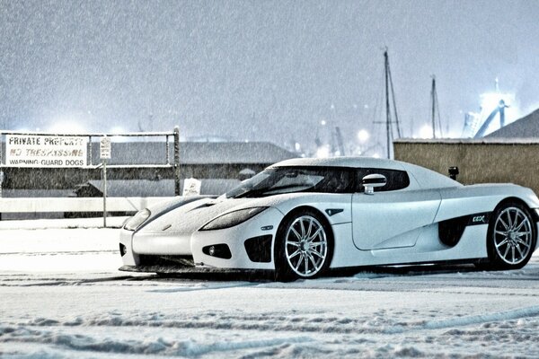 Samochód zimą. Biały samochód na tle śniegu. Supersamochód. Fajne autko. Koenigsegg