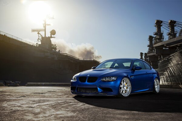 Niebieski BMW M3, na tle słońca i dymu