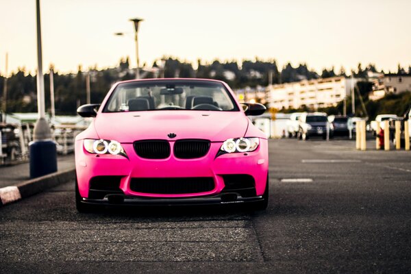 Różowe BMW z anielskimi oczami zamiast for stoi na poboczu drogi