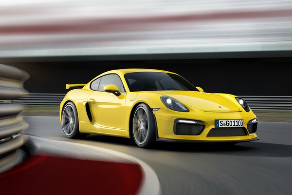 Żółte Porsche Cayman z dużą prędkością wchodzi w zakręt