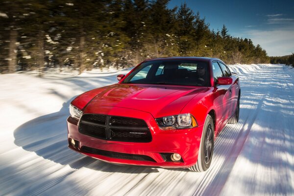 Un coche rojo conduce por un camino nevado