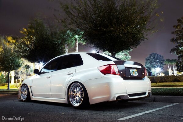 Subaru Impreza blanco en las luces de la ciudad nocturna