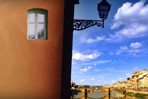 Lantern on the wall of the house against the background of an ancient bridge