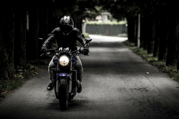 A biker wearing a helmet on a motorcycle rides on the road