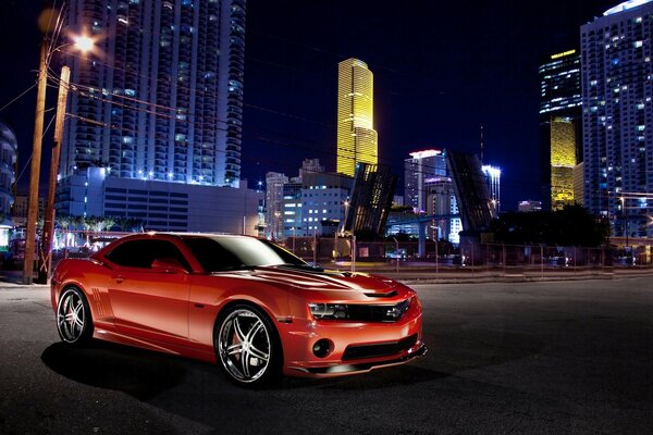 Chevrolet camaro rojo en el fondo de la ciudad de la noche