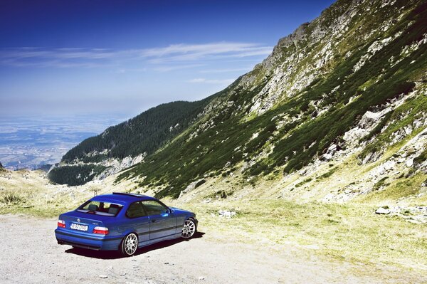 The blue color of the car on the background of mountains