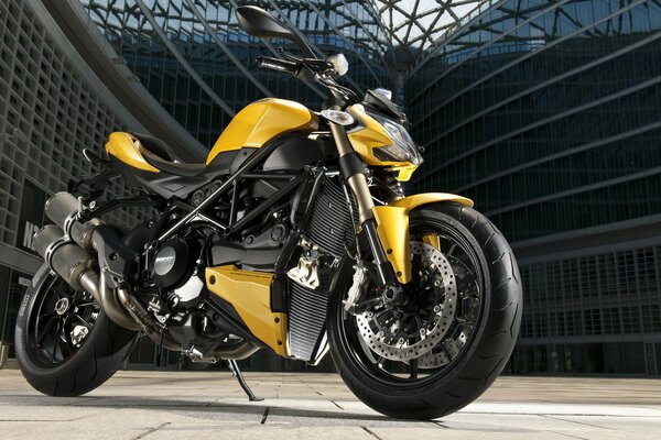 Une moto ducati streetfighter jaune se dresse sur un fond urbain