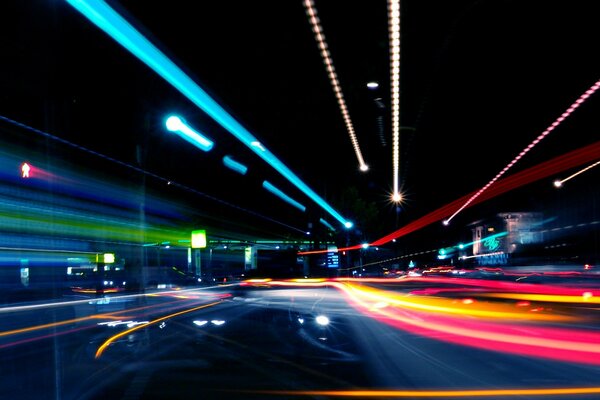 Guida notturna in auto alla luce delle luci al neon della metropoli