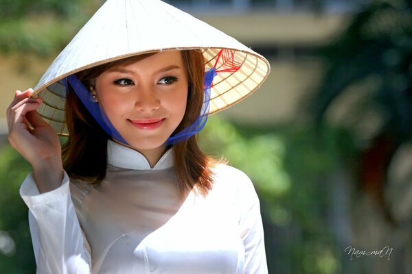 Lächelnde süße asiatische Frau in einem vietnamesischen Hut