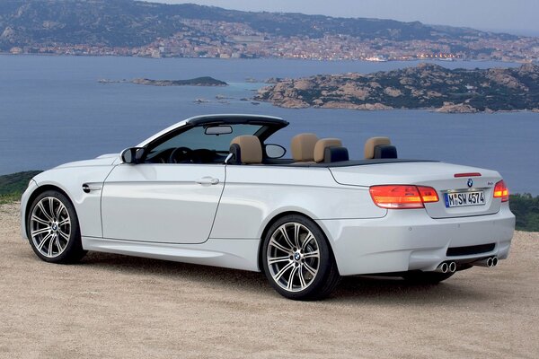 Blanco convertible BMW M3. hermosa vista de la ciudad de la noche y el mar