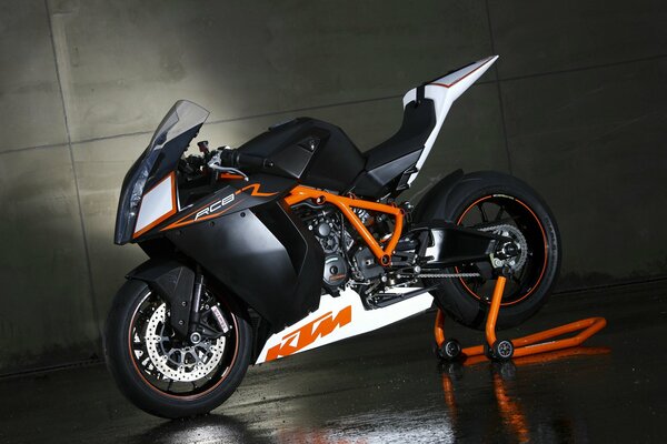 The 2009 KTM rc8 motorbike stands against a concrete wall