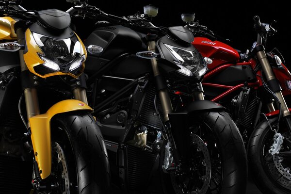 Жёлтый чёрный и красный мотоциклы ducati streetfighter стоят в ряд