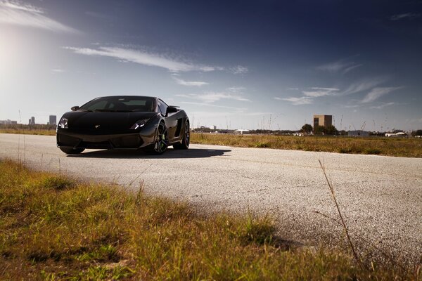 An asphalt road with a curb on which there is a Lamborghini Aventador