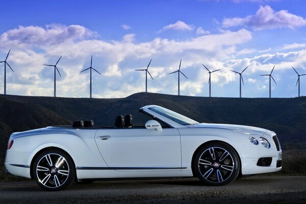 White car side view on the background of wind turbines