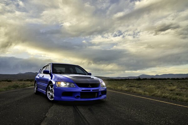 Blue Mitsubishi on the road among the clouds