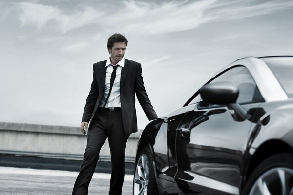 A man poses for a photo with a car