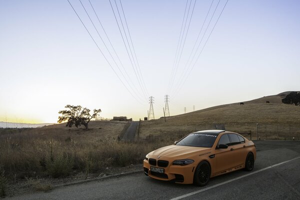 Gelber bmw m5 auf dem Hintergrund der Stromleitungen