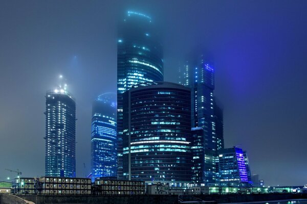 Moscow s night skyscrapers burning with lights in the fog