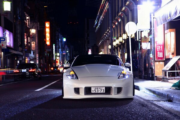 Blanco Nissan 370Z con ruedas Vossen se encuentra en la calle de la noche