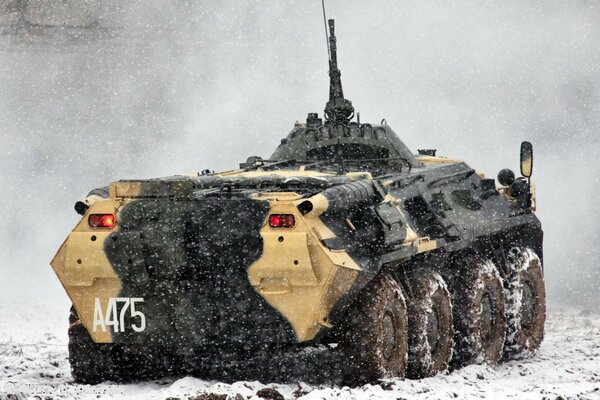 Armored personnel carrier rides on a snowy road in a snowfall